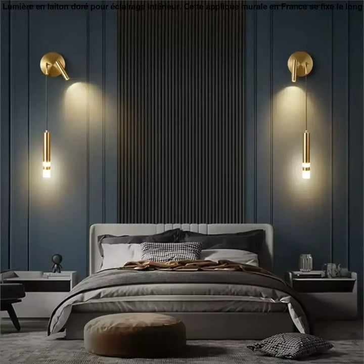 Applique murale en laiton aurelia avec luminaires cylindriques dorés encadrant un miroir sur un mur bleu marine