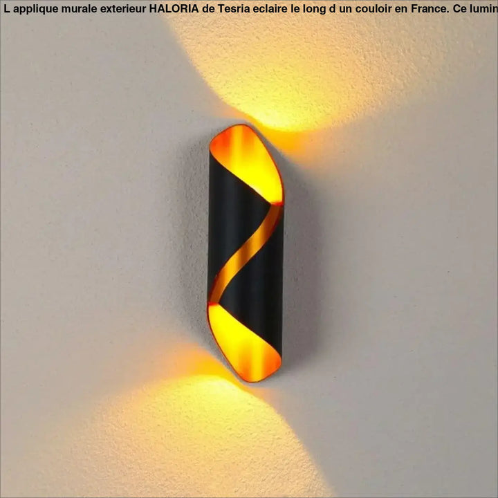 Applique murale exterieur haloria noire et dorée torsadée émettant une lumière ambiante chaude en extérieur
