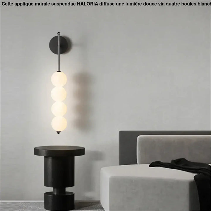 Applique murale suspendue noire avec quatre boules blanches en verre disposées verticalement haloria