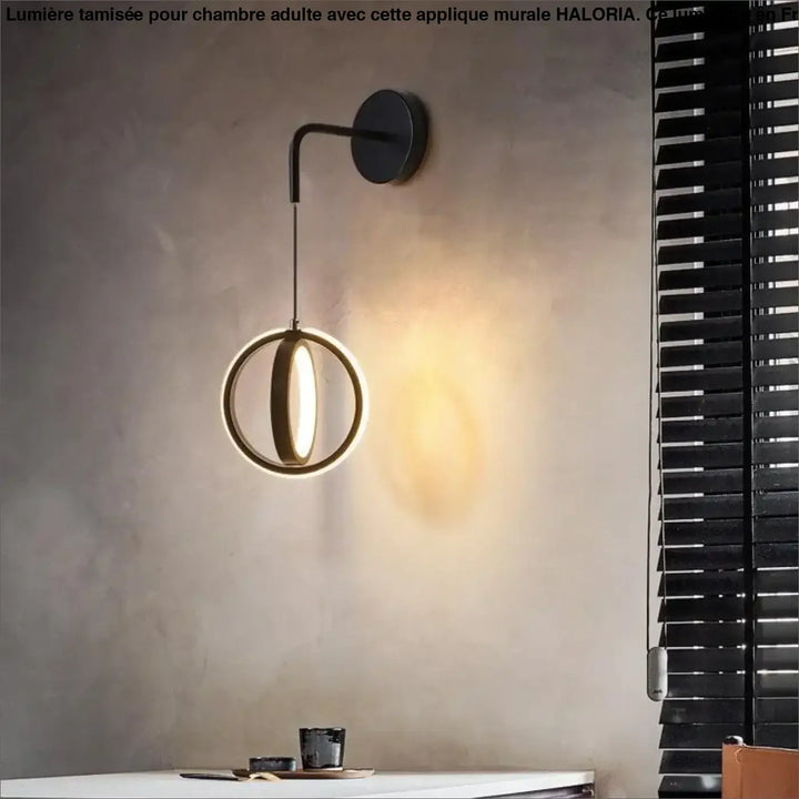 Applique murale noire moderne avec anneau circulaire émettant une lumière ambiante chaude pour chambre adulte haloria