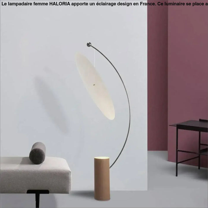 Femme lampadaire moderne avec bras métal noir incurvé et diffuseur ovale écru côté d’un canapé