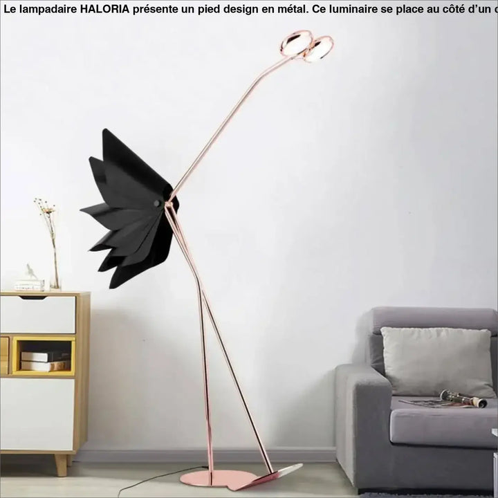 Lampadaire sur pied design haloria rose gold avec abat-jour noir en forme de feuille à côté d’un canapé