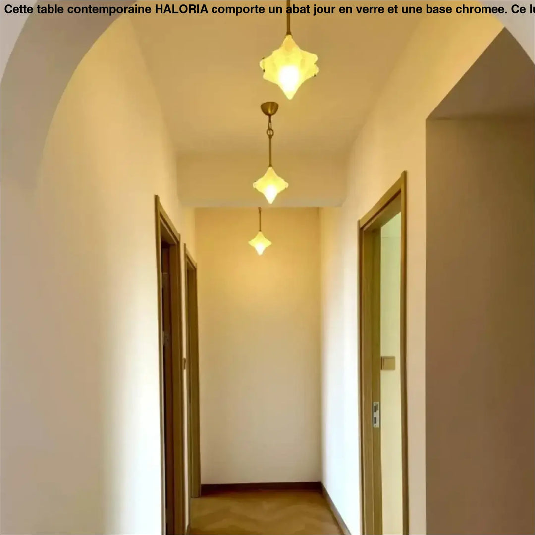 Trois suspensions luminaires petales en verre transparent aux tons chauds offrent un éclairage doux dans un couloir