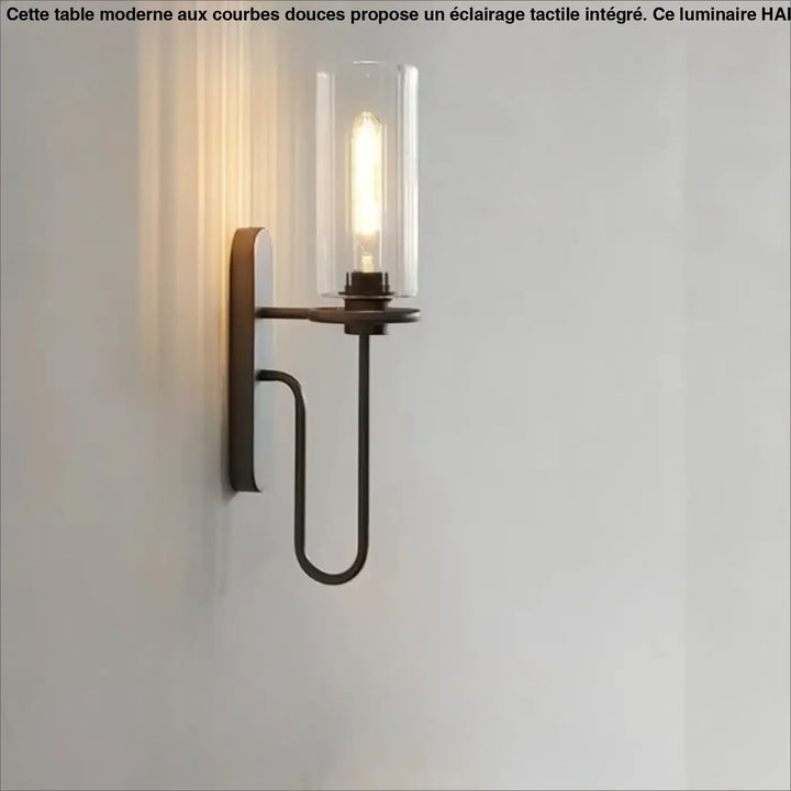Applique murale loftia en bronze foncé avec bras métallique courbé et cylindre en verre clair abritant une ampoule filament