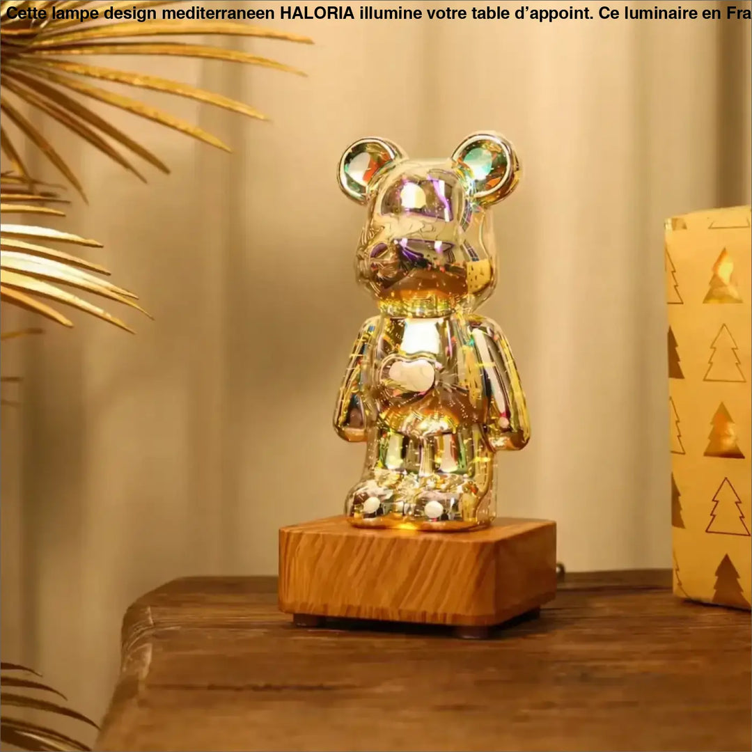 Lampe ourson décorative en figurine dorée irisée avec motif cœur, posée sur base en bois, offrant effets lumineux multicolores