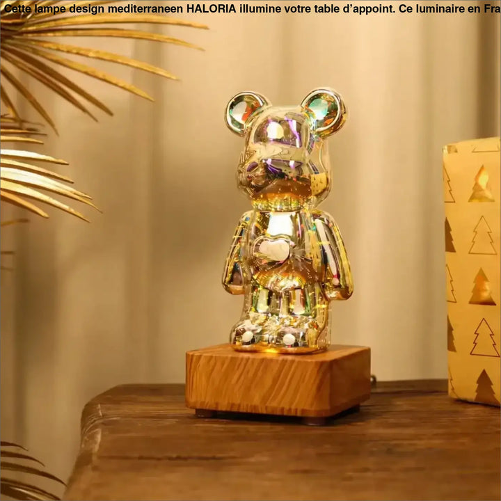 Lampe ourson décorative en figurine dorée irisée avec motif cœur, posée sur base en bois, offrant effets lumineux multicolores