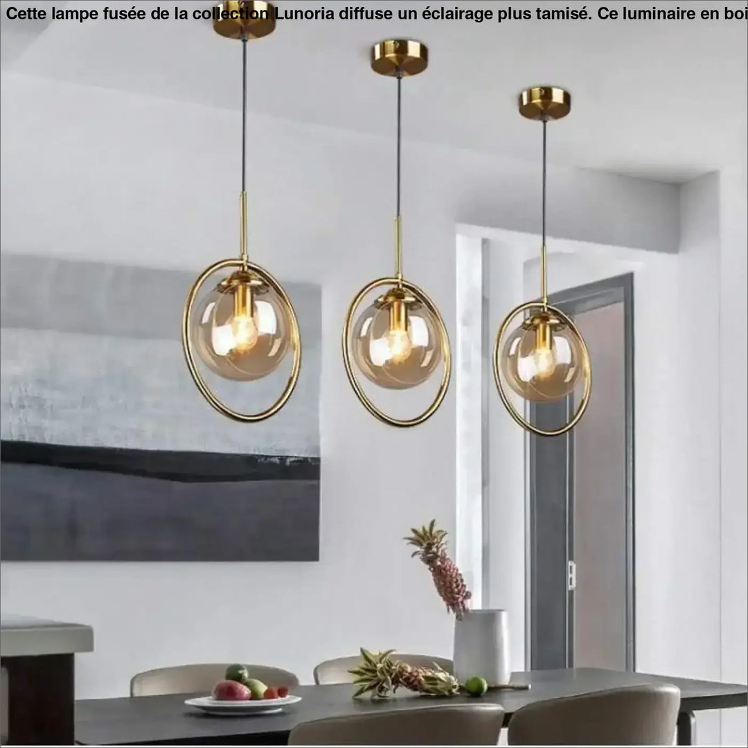 Three lampe fusee pendant lights with gold metal frames and amber glass globes for éclairage plus and table d’appoint
