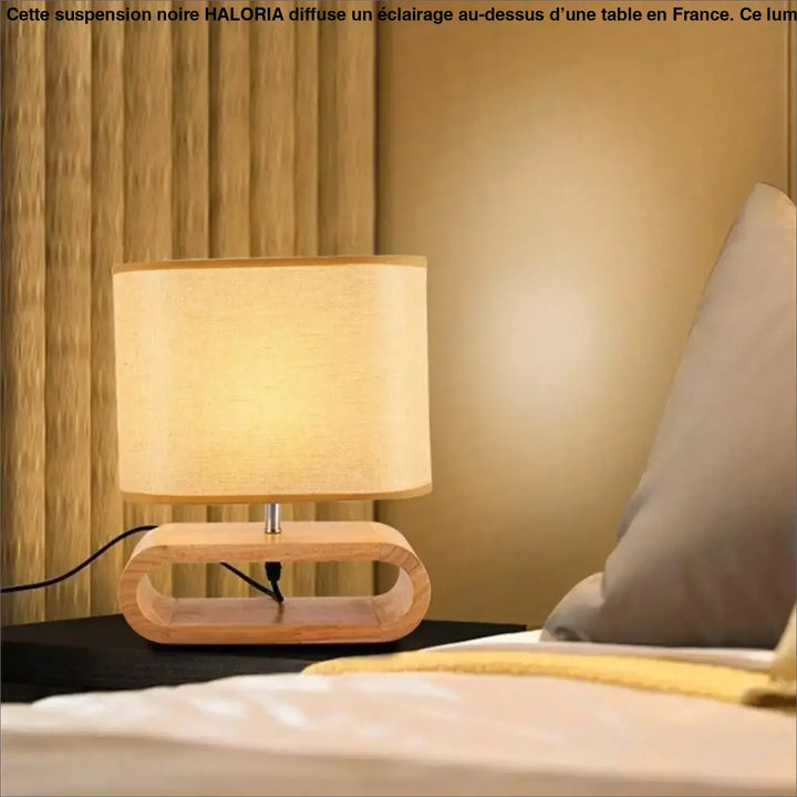 Lampe suspendue noir avec base courbée et abat-jour cylindrique en tissu beige au-dessus d’un coin salon