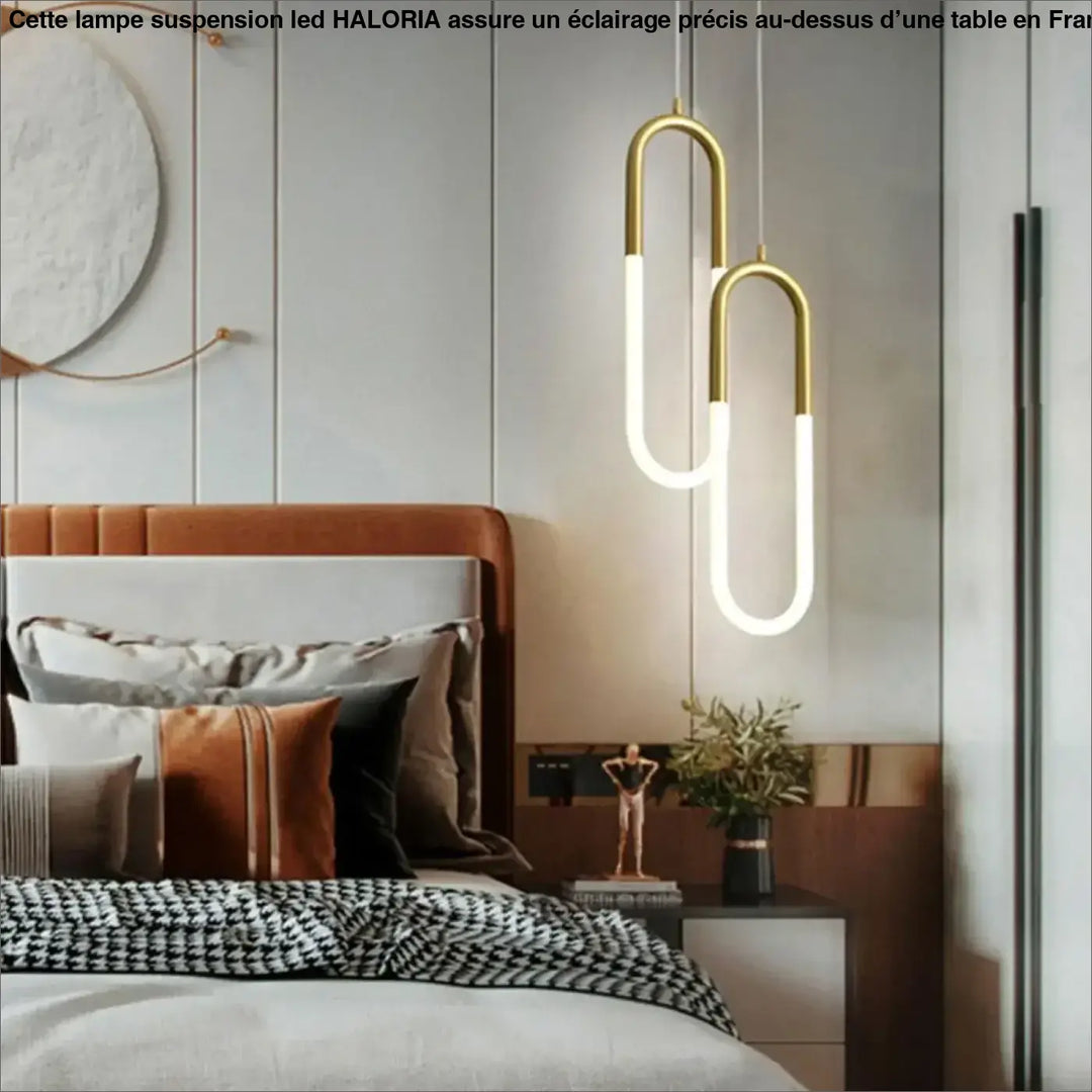 Lampe suspension led haloria avec tubes en verre blanc illuminés et structure u en métal doré suspendue au-dessus du lit
