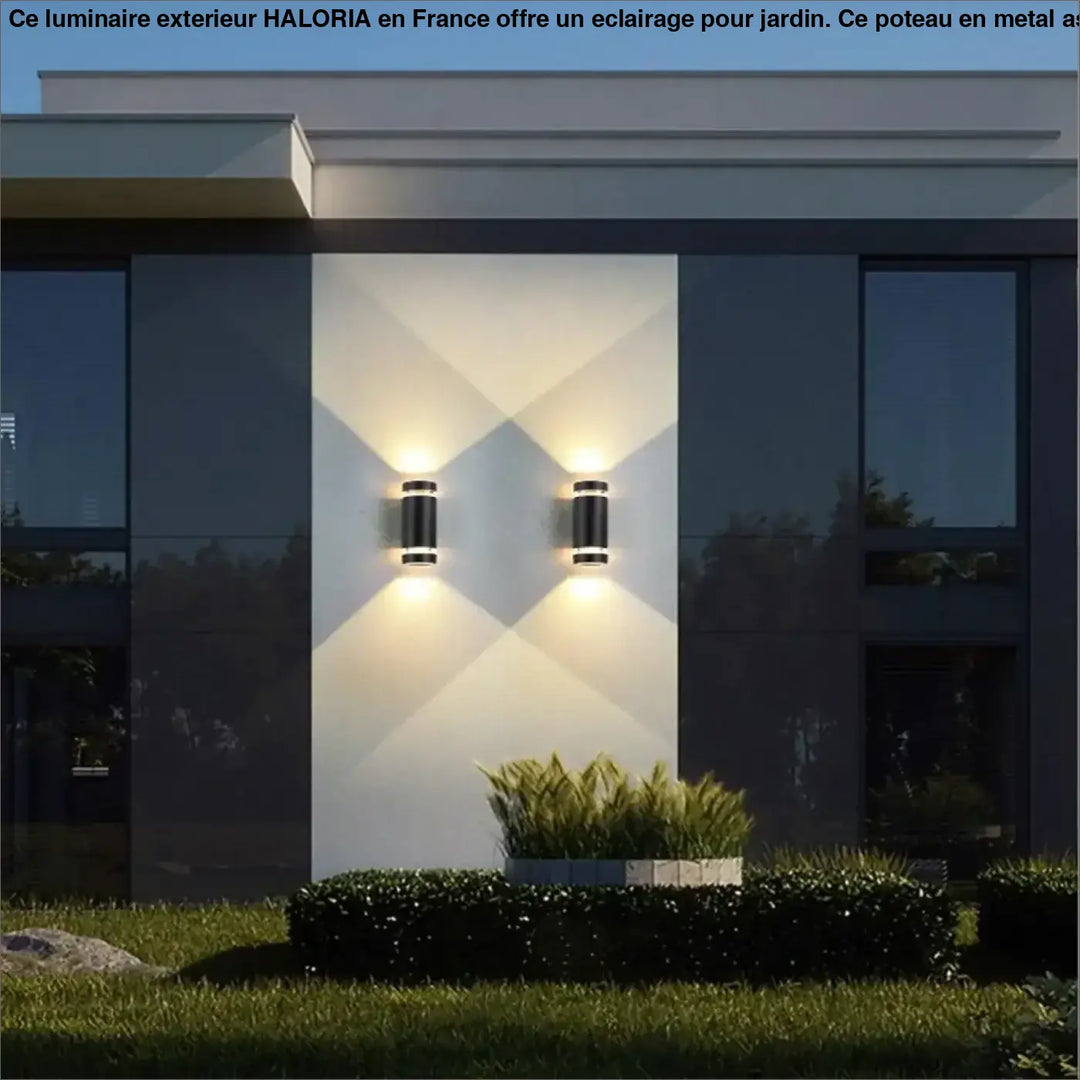 Poteau pour luminaire exterieur haloria avec appliques murales cylindriques noires et éclairage chaud côté d’un canapé