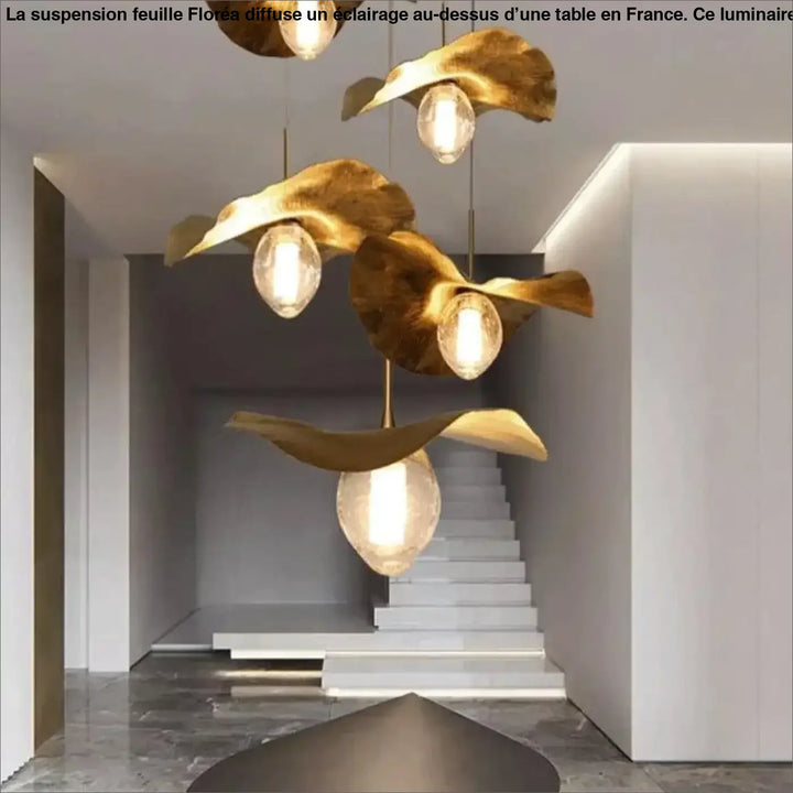 Suspension feuille floréa avec pendentifs feuilles dorées et ampoules verre clair suspendues au-dessus d’une table ou d’un coin salon