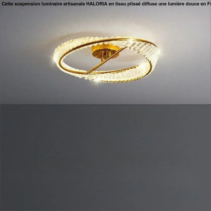 Lustre au plafond à finition dorée, doté de deux anneaux concentriques ornés d’éléments transparents, facettés, façon cristal.