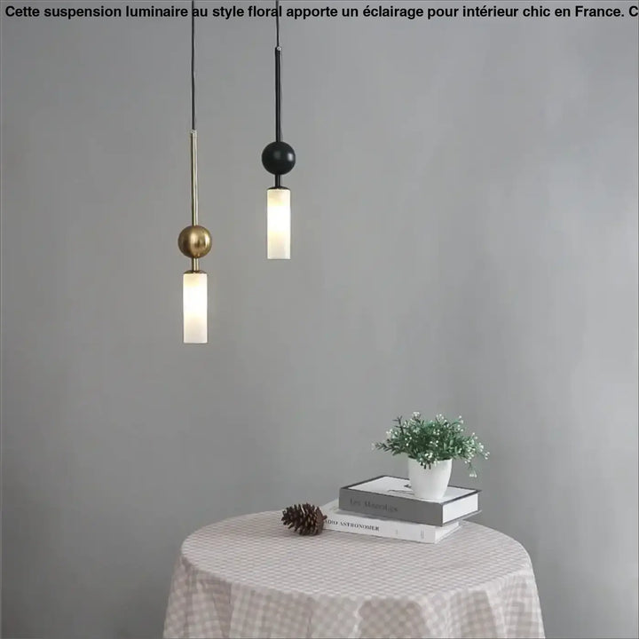 Suspension luminaire krysta avec deux boules métalliques minimalistes en laiton et noir suspendues au-dessus d’une table