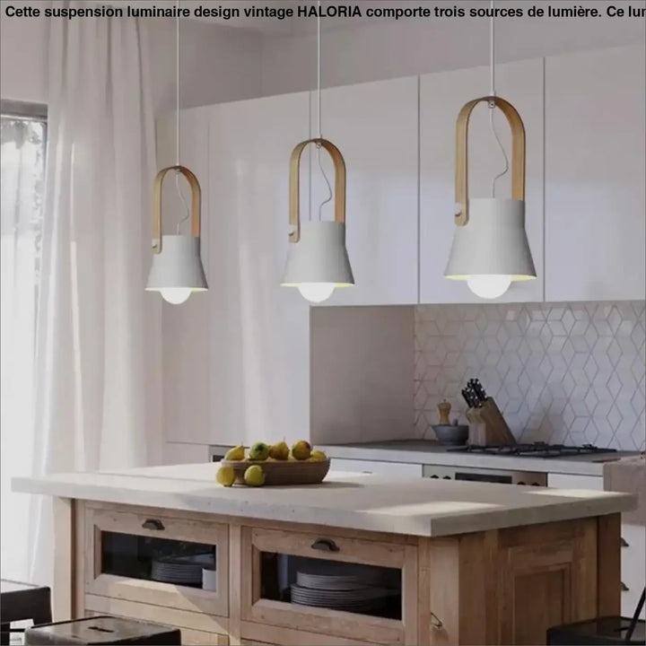 Trois suspensions luminaire design vintage avec abat-jours blancs en forme de cloche et cadres u en bois clair au-dessus d’un îlot de cuisine
