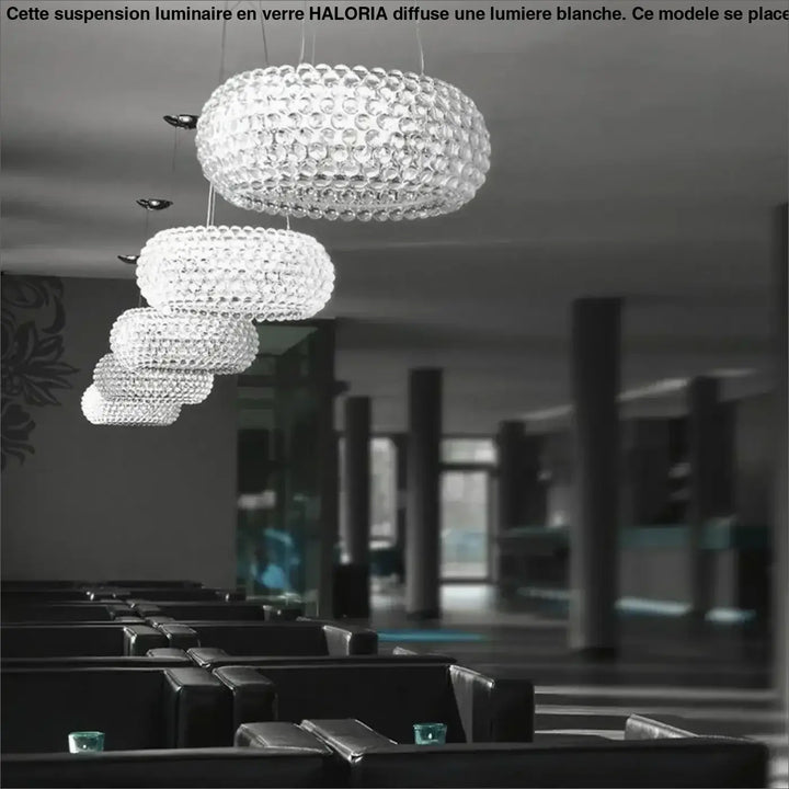 Suspension luminaire en verre facetté clair avec lumiere blanche au-dessus d’une table design sphérique moderne haloria