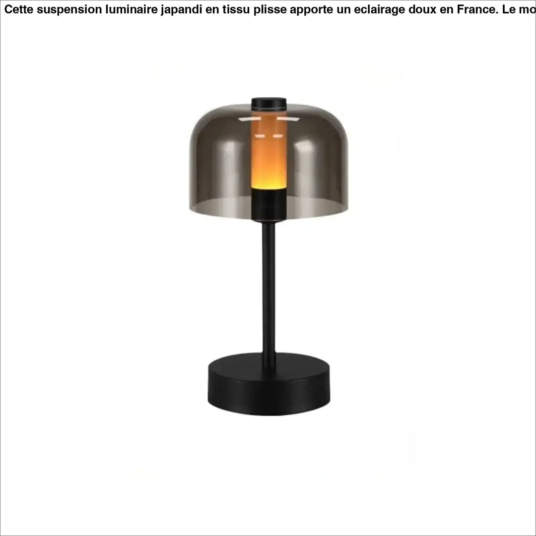Lampe de table cristo en métal noir avec abat-jour en verre fumé diffusant une lumière orange chaleureuse idéale comme veilleuse