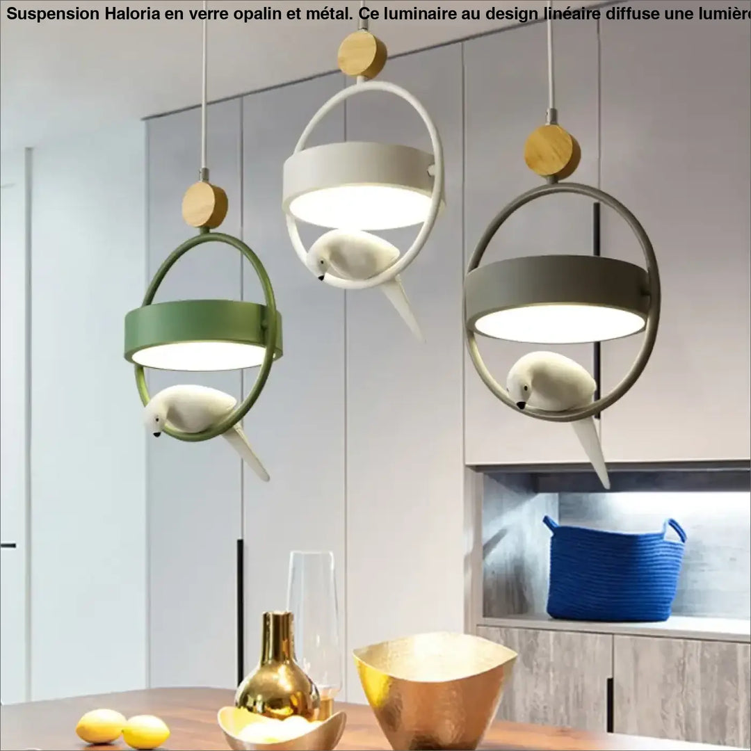 Suspension luminaire lineaire en verre opalin avec cadres metalliques circulaires et oiseaux ceramiques blancs au-dessus d’une table