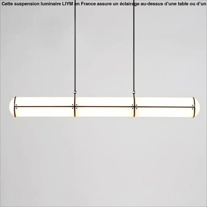 Suspension luminaire moderne avec design cylindrique allongé, verre dépoli et cadre métal noir au-dessus d’une table