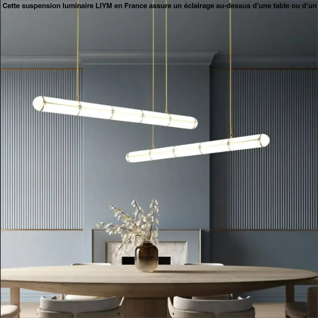 Suspension luminaire avec chaines dorées et abat-jour cylindrique en verre blanc au-dessus dune table ou dun coin salon