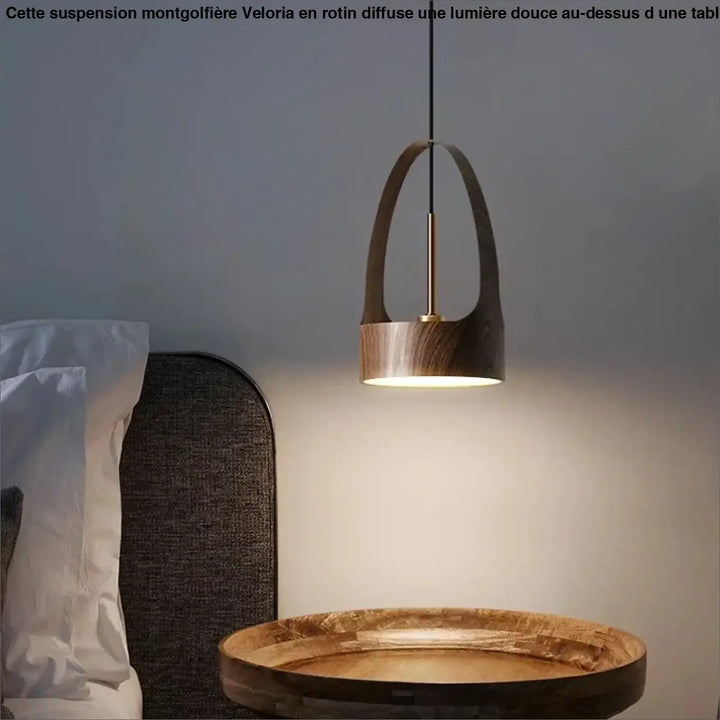 Suspension luminaire montgolfiere design avec panier en rotin en bois foncé et laiton suspendue au-dessus d’une table ronde en bois
