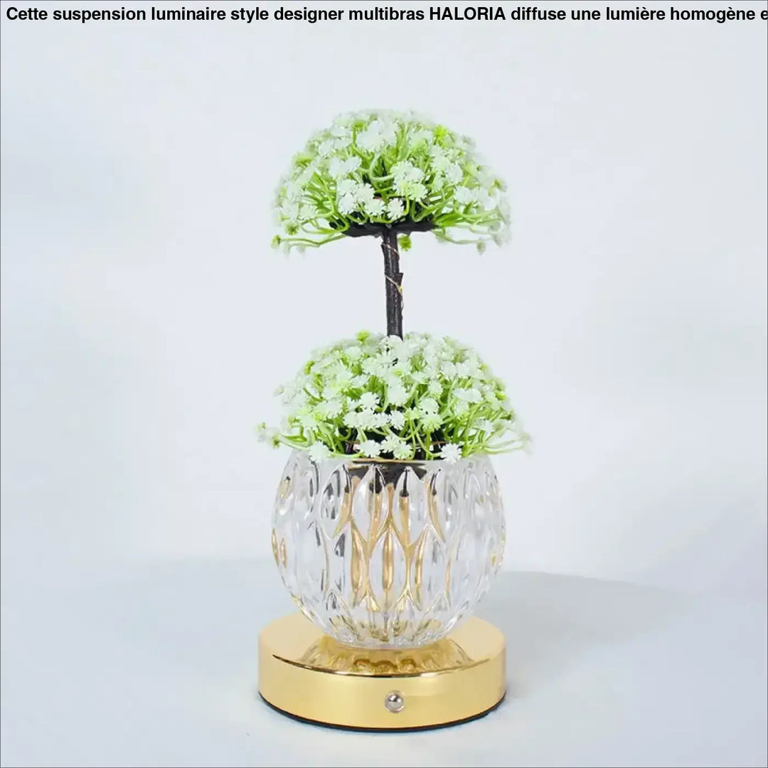 Lampe de table tulyna avec vase en verre facetté clair et base dorée tenant des fleurs blanches, source de lumière décorative