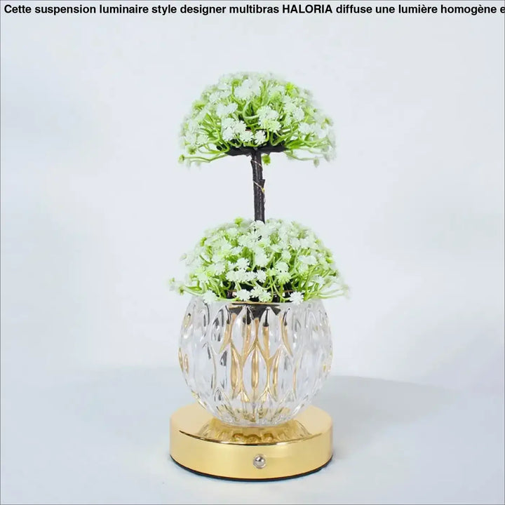 Lampe de table tulyna avec vase en verre facetté clair et base dorée tenant des fleurs blanches, source de lumière décorative